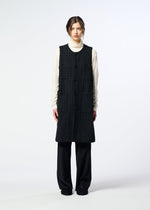 A person stands facing forward, wearing the HaaT SAKIORI long sleeveless woven vest over a cream turtleneck, loose black pants, and black shoes against a plain light background.