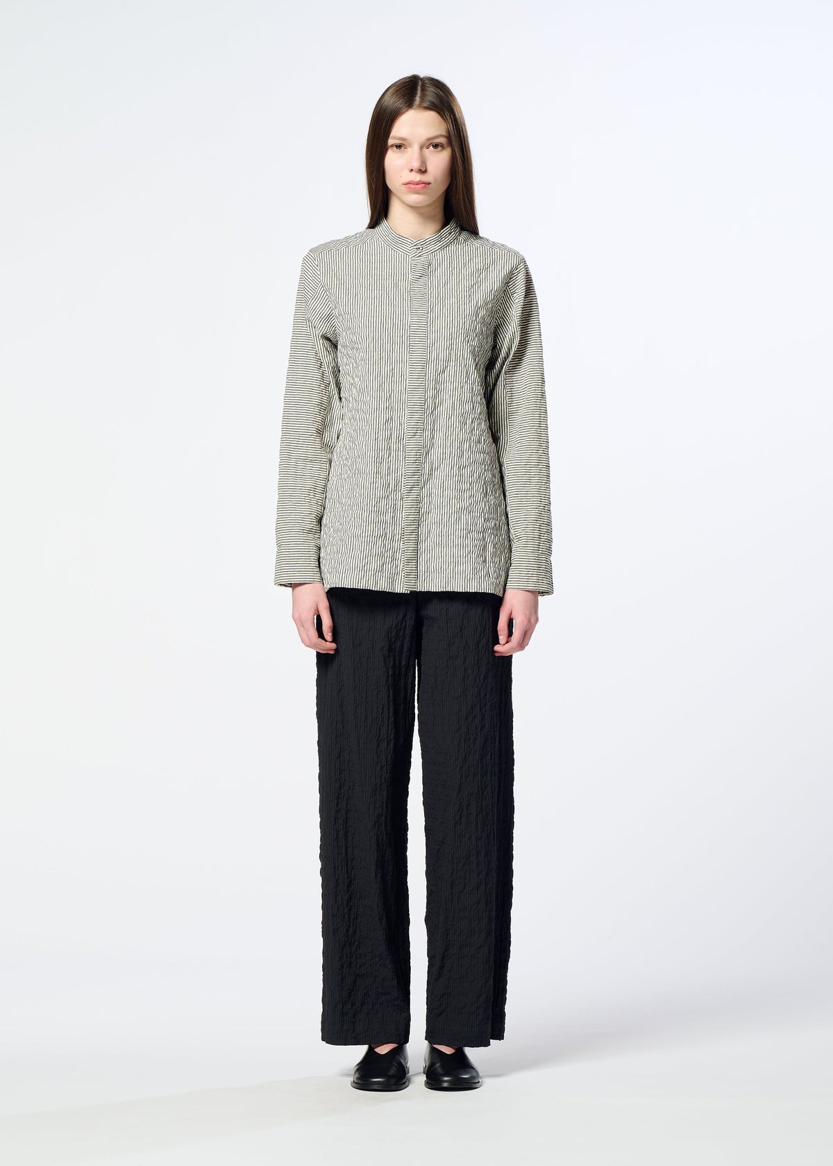 A person stands facing forward wearing the HaaT RIPPLE STRIPE light gray textured long-sleeve top, loose black seersucker pants, and black shoes against a plain light background. view 6 of 8
