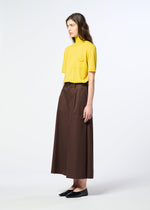 A person stands sideways against a plain white background, wearing a yellow short-sleeve top with a chest pocket, black shoes, and brown COTTON STRETCH BOTTOM pants from HaaT crafted from organic cotton.