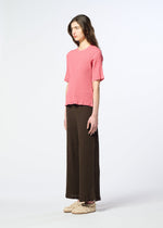 A person stands in profile against a plain background, wearing a pink textured short-sleeve top, light-colored shoes, and brown KYO CHIJIMI AUGUST pants by HaaT featuring a distinct crinkled texture.