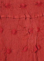 Crafted by HaaT, the KYO CHIJIMI SQUARE EMB features red textured fabric with a crinkled appearance and raised, round tufted dots evenly distributed across the surface. Reminiscent of classic KYO CHIJIMI pants, this material has a subtly uneven, gathered finish that enhances its distinctive crinkled texture, adding both depth and visual interest.
