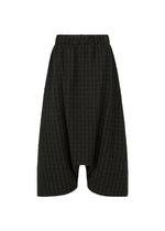 The HaaT SAKIORI is a black knee-length skirt in woven fabric with a wide silhouette, elastic waistband, subtle pinstripes, and an irregular hem for a draped look. Photographed on a plain white background. - BLACK （no.15）