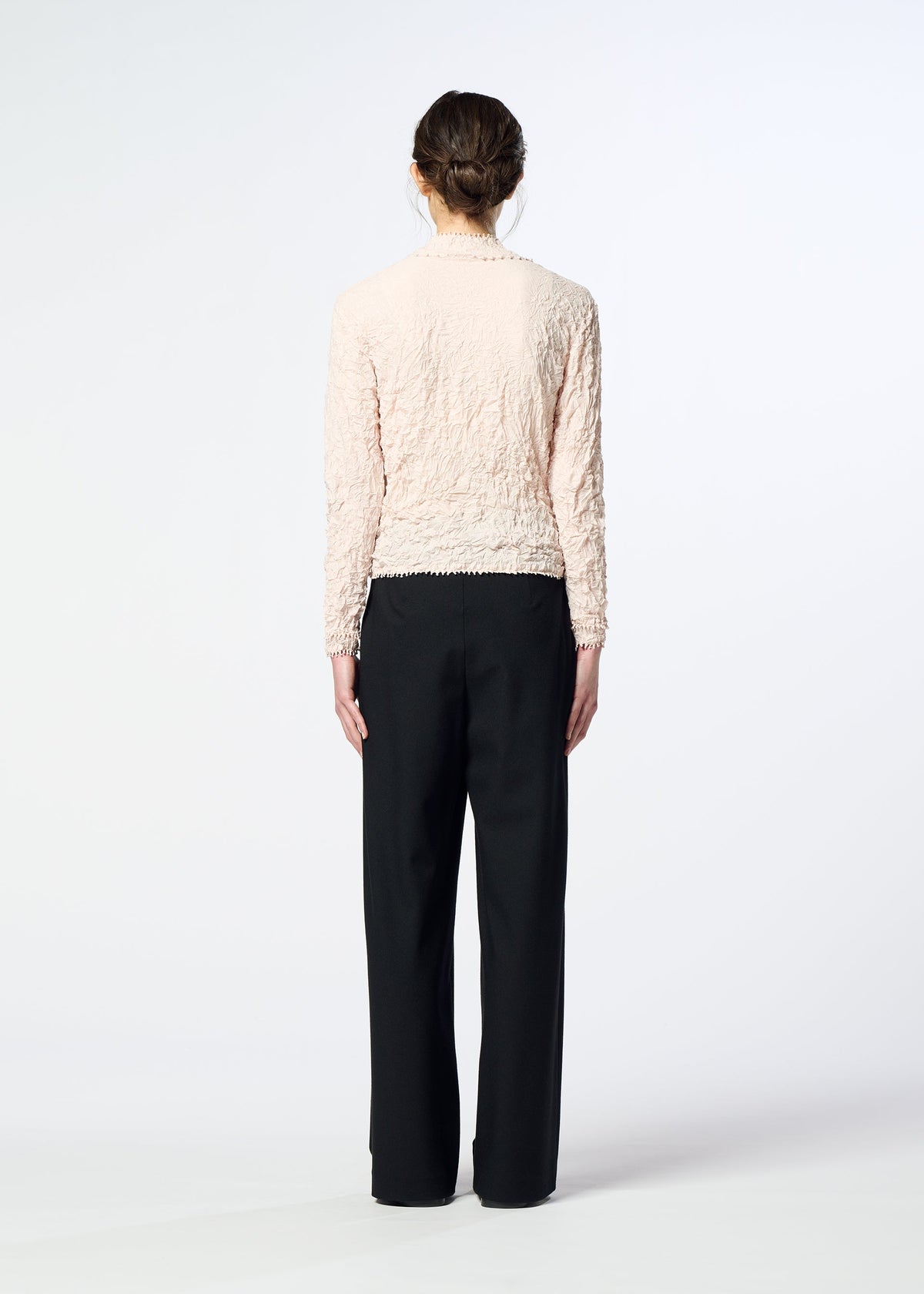 Zoomed view A woman stands with her back to the camera, wearing a textured light pink long-sleeve top and HaaT FLANNEL BOTTOM pants against a plain white background.