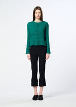 A person stands facing forward against a white background, wearing a green long-sleeve buttoned top, HaaT’s KYO CHIJIMI TSUCHIKABE pants with textured hems for a crepe-like feel, and black shoes.