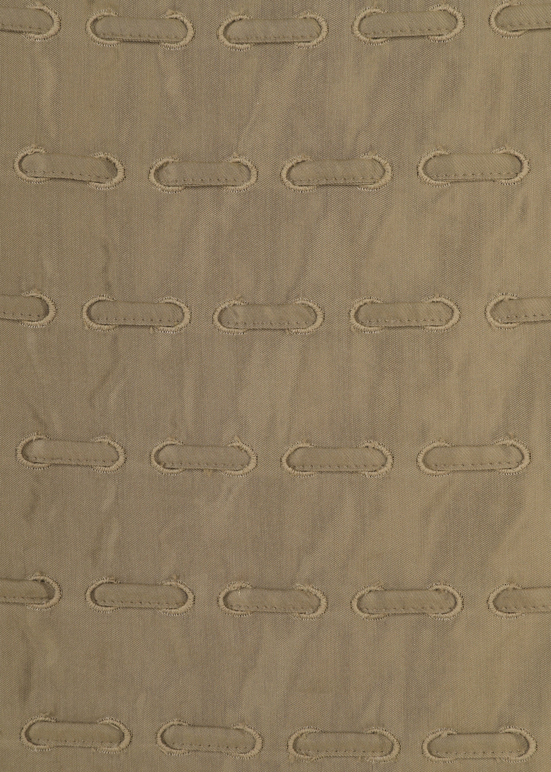 Zoomed view HOLE & LINE by HaaT features a soft beige fabric with subtle vertical ridges, adorned with evenly spaced horizontal oval stitched holes that create a grid-like pattern reminiscent of eyelet embroidery.