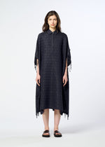A person stands facing forward against a plain white background, wearing the HOLE & LINE dress by HaaT—a loose, textured, dark midi poncho-style design featuring short sleeves and side ties—paired with black sandals.