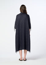 A person stands facing away against a plain white background, wearing HaaT’s HOLE & LINE textured, loose-fitting poncho-style dress with elbow-length sleeves and black sandals.