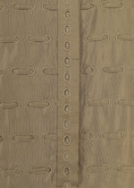 Close-up of the HOLE & LINE fabric by HaaT, showcasing tan or khaki twill material with horizontal embroidered oval cutouts and a vertical central strip adorned with a row of matching oval holes. This eyelet embroidery brings delicate detail to the soft texture and repeating pattern, evoking styles seen in poncho-style dresses.