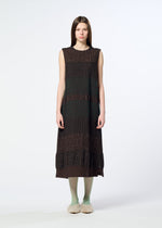 A woman stands facing forward against a plain white background, wearing the HaaT COLLAGE STRETCH Ⅰ sleeveless dark brown midi dress with a subtle check pattern, paired with light green tights and beige fuzzy slippers.