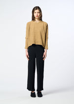 A woman stands facing forward, wearing the HaaT KYO CHIJIMI 2WAY loose round-neck long-sleeved top and black wide-leg pants with black shoes, against a plain light background.