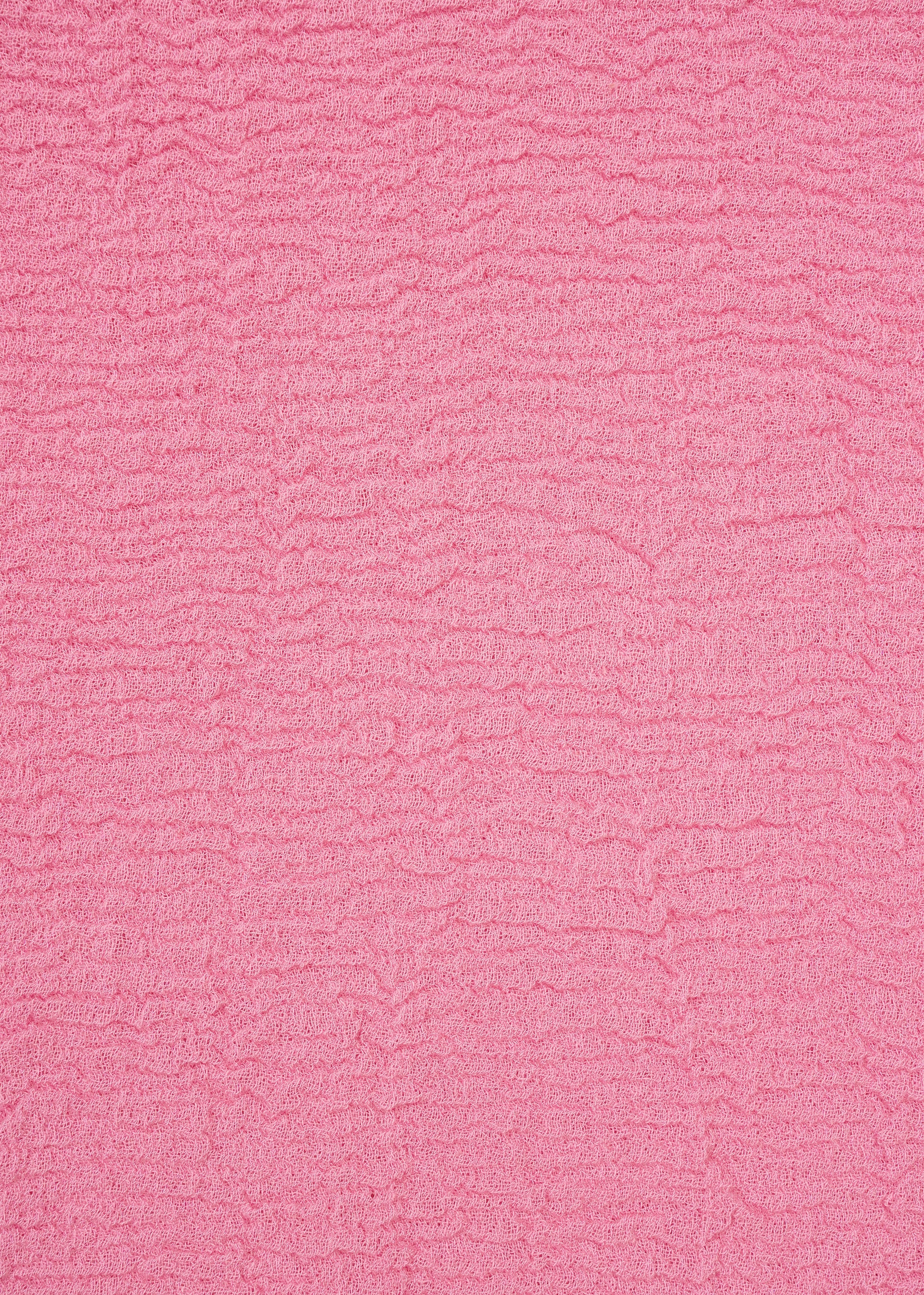Zoomed view A close-up of a textured pink fabric with horizontal ripples and small wrinkles, creating a soft, wavy surface pattern across the entire image—distinctive of the unique product dyeing process used for the HaaT KYO CHIJIMI 2WAY top.