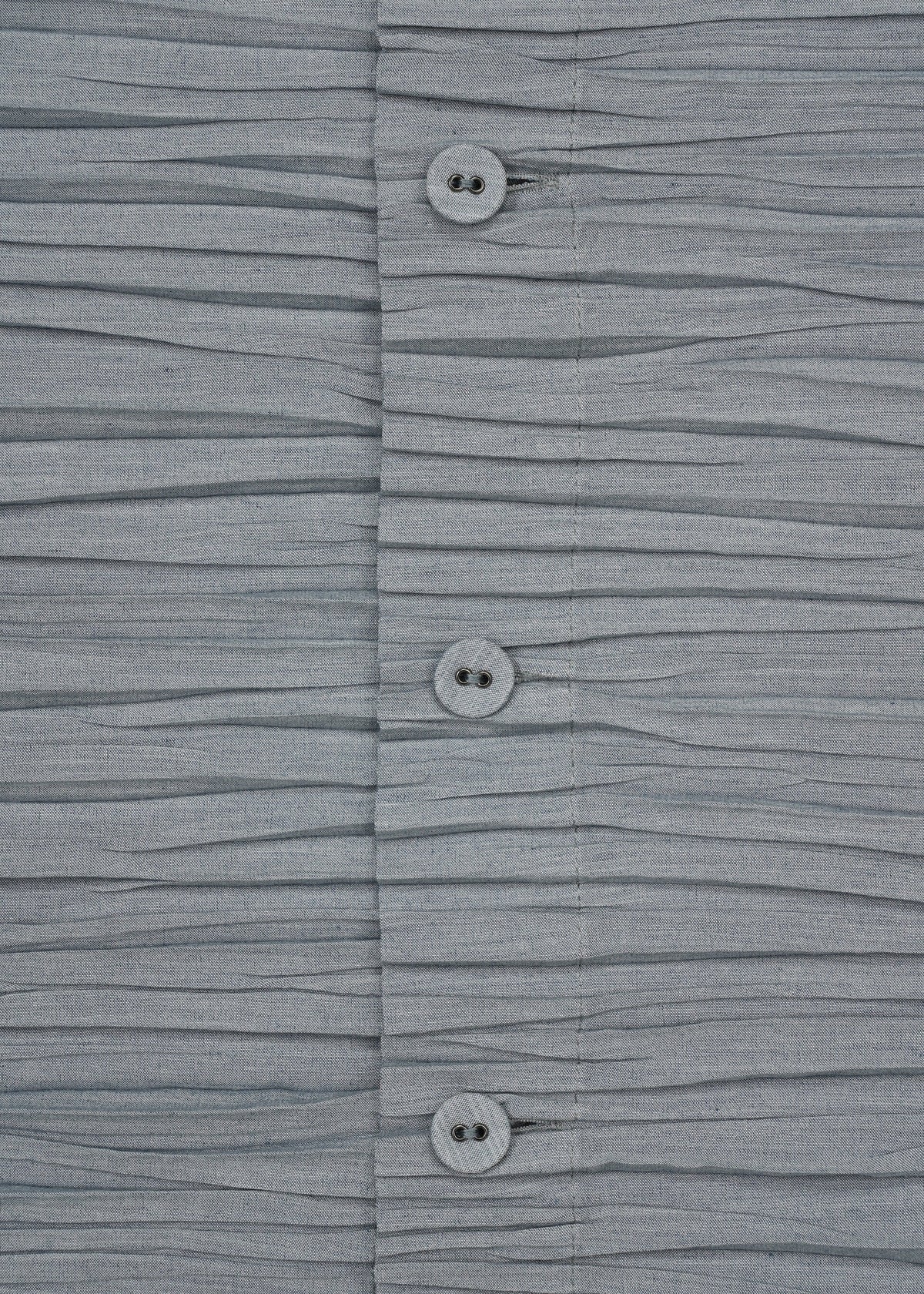 Close-up of the SHIBARI SHIRT by HaaT, a gray short-sleeved top featuring horizontal pleats and three buttons in the center. Crafted from recycled polyester for an eco-friendly touch, its soft texture and pleated arrangement create a wavy effect across the material. view 6 of 10