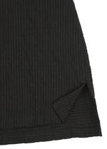 Close-up of the hem of HaaT’s RIPPLE STRIPE fabric in black, featuring a wave striped pattern and a small triangular slit at the edge that reveals an inner layer.