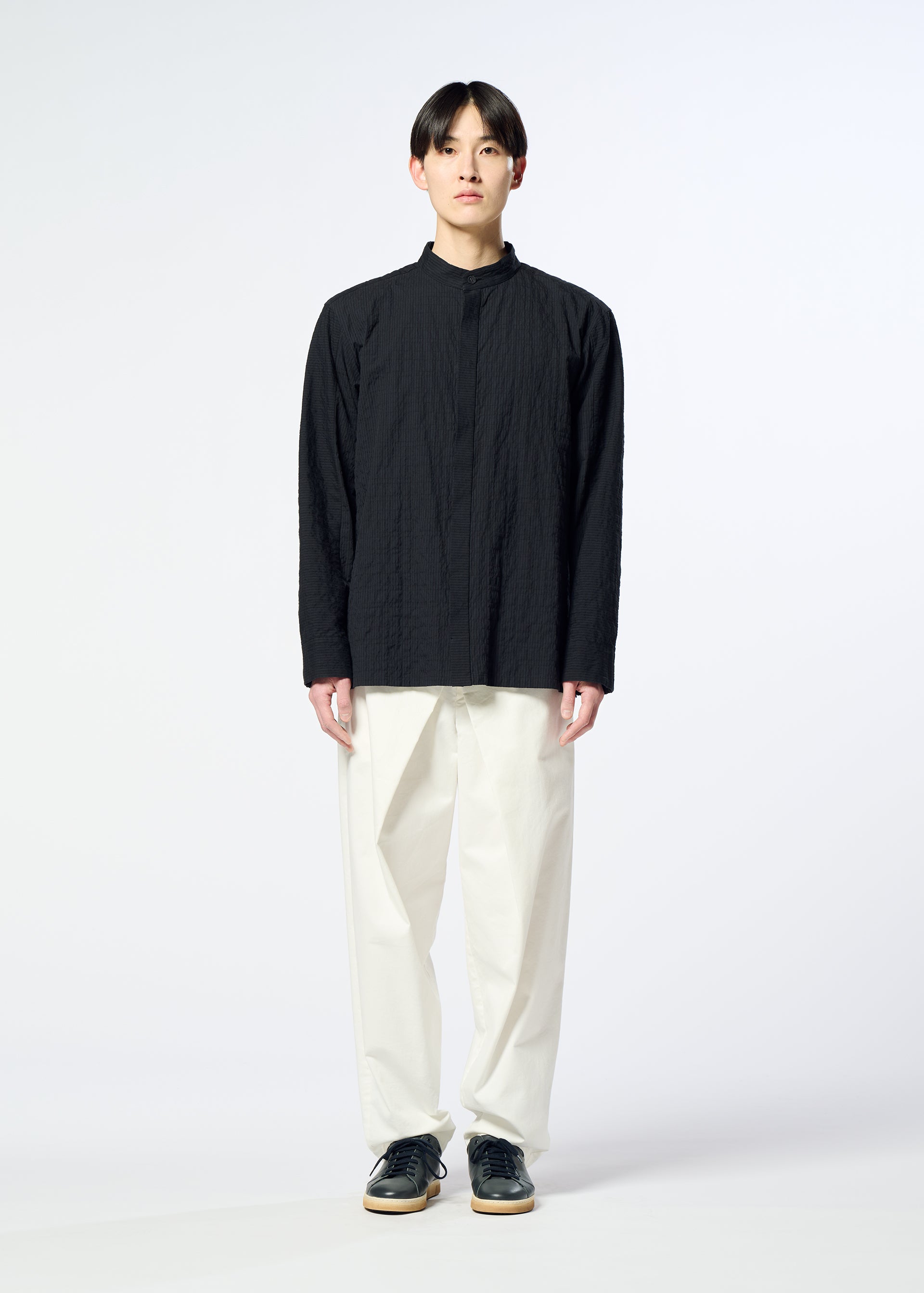 Zoomed view A person stands facing forward, wearing the HaaT RIPPLE STRIPE black long-sleeved unisex shirt, paired with loose white pants and black shoes against a plain light background.