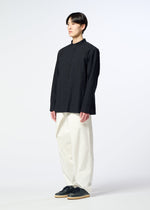 A person stands against a plain white background, wearing HaaT’s RIPPLE STRIPE black long-sleeved shirt, loose white pants, and black shoes, looking forward with a neutral expression.