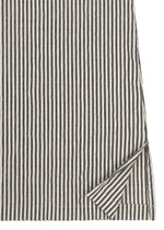 A close-up of HaaT’s RIPPLE STRIPE fabric from a long-sleeved shirt, featuring bold black and white vertical stripes; one corner is slightly folded to reveal that the reverse side displays the same stripe pattern.