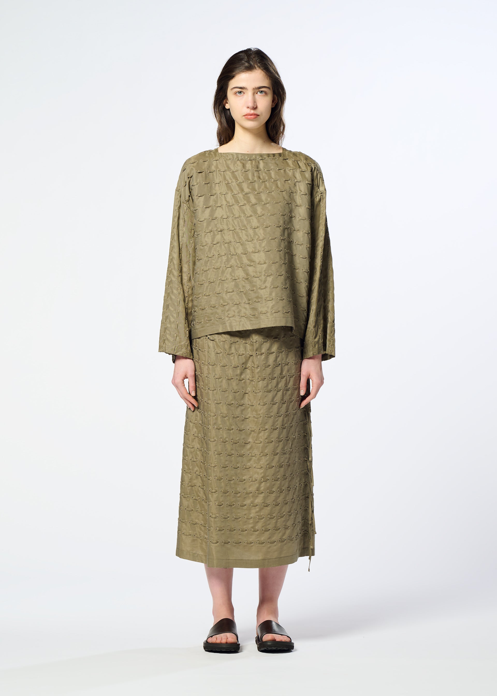Zoomed view A person stands facing forward, wearing the HOLE & LINE cupra-blend textured long-sleeve top and matching long skirt by HaaT in olive green, paired with black sandals, against a plain light background.