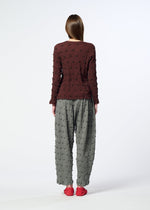 Wearing the KYO CHIJIMI SQUARE EMB top by HaaT, a person stands with their back to the camera in a crinkled brown shirt, loose gray textured pants, and red shoes against a plain white background.