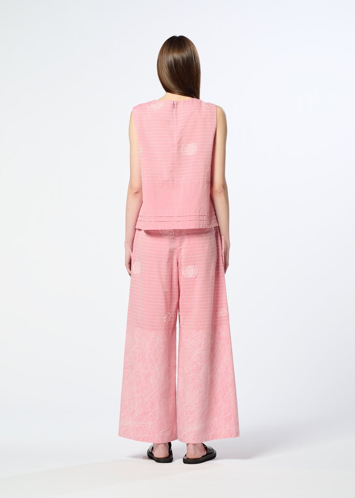 A person with long, straight hair faces away, wearing HaaT's ONE STROKE DRAW jacquard sleeveless top and matching wide-leg pants in a textured cotton cupra blend, paired with black sandals against a plain white background. view 6 of 6