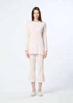 A woman faces forward in a pale pink KYO CHIJIMI TSUCHIKABE set by HaaT, featuring a crepe-textured, ultra-fine cotton top and cropped ruffle pants. She completes the look with light green slip-on shoes.