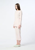 A woman with straight brown hair stands sideways in a long-sleeved, pale pink KYO CHIJIMI TSUCHIKABE set from HaaT, featuring subtle ruffles and a crepe-like texture, paired with light green slip-ons against a plain white background.