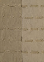 The HOLE & LINE textile by HaaT features two vertical fabric panels—one tan and one light beige—expertly stitched together. Each panel is embellished with rows of oval-shaped cutouts framed by embroidered edges, forming a delicate eyelet embroidery pattern that repeats across the textured surface.