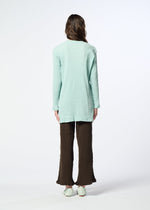 A person stands facing away, wearing the HaaT KYO CHIJIMI AUGUST long light blue cardigan with a crinkled texture, paired with brown textured pants and light-colored shoes. The background is plain white.