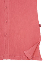 Close-up of the HaaT KYO CHIJIMI AUGUST cardigan, crafted from textured pink fabric, featuring buttons along the left side and a slightly folded bottom right corner that reveals the inside’s distinctive crinkled texture.