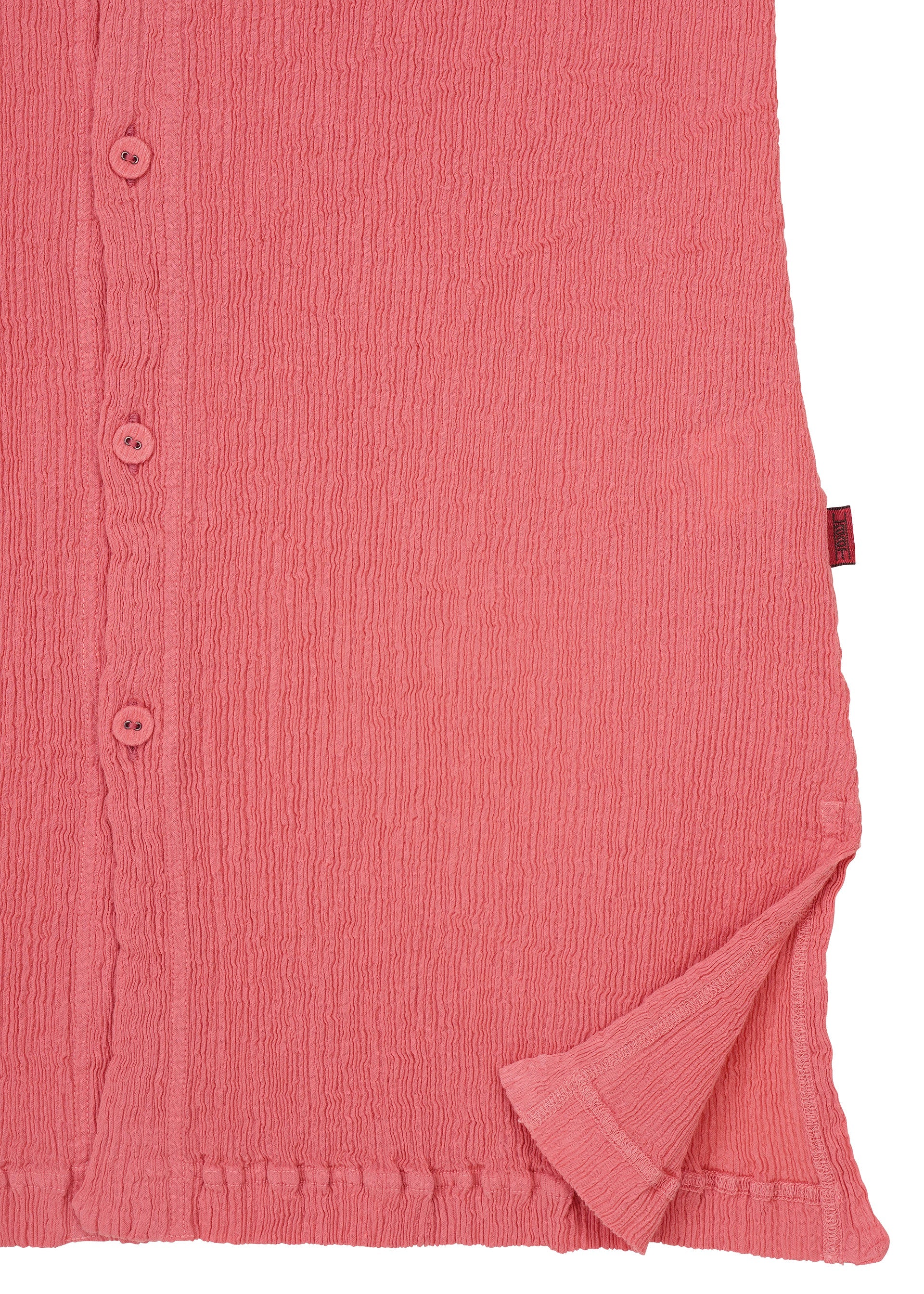 Zoomed view Close-up of the HaaT KYO CHIJIMI AUGUST cardigan, crafted from textured pink fabric, featuring buttons along the left side and a slightly folded bottom right corner that reveals the inside’s distinctive crinkled texture.