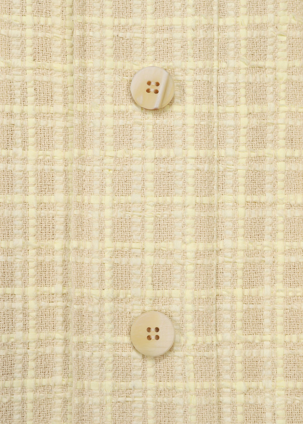 Zoomed view Close-up of SAKIORI by HaaT: light yellow woven fabric with a checkered texture, made with traditional techniques, featuring two beige buttons vertically aligned at the center.