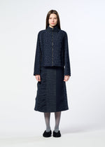 A woman stands facing forward against a plain white background, wearing HaaT’s COLLAGE STRETCH Ⅰ navy blue jacquard-patterned jacket and matching midi skirt, paired with gray tights and black shoes.