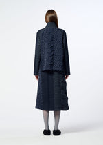 A person with long brown hair stands facing away against a plain white background, wearing HaaT’s COLLAGE STRETCH Ⅰ—a navy blue patterned outfit featuring jacquard weaving and textured details.