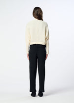A person with long brown hair, seen from behind, wears a cream-colored HaaT KYO CHIJIMI 2WAY bolero-style cardigan with a subtle crinkle texture and black pants. They stand on a white background with their arms relaxed by their sides.