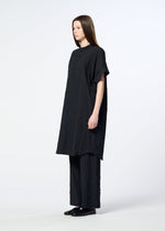 A person with straight brown hair wears the HaaT RIPPLE STRIPE loose, textured black seersucker tunic and matching wide-leg pants with black flat shoes, standing against a plain, light background.