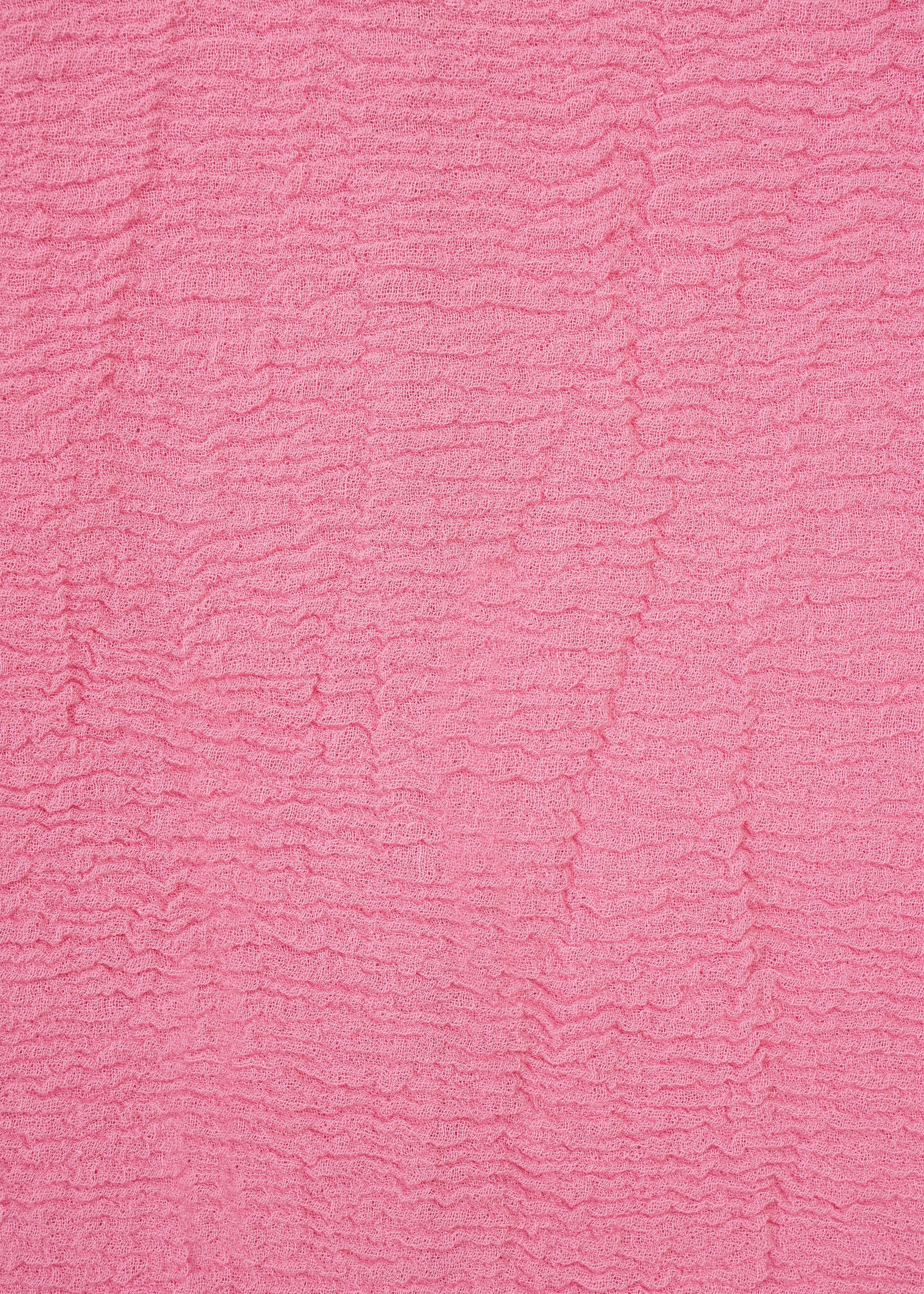 Zoomed view Textured pink fabric from HaaT’s KYO CHIJIMI 2WAY collection, featuring horizontal rippled lines that form a wavy pattern across the surface. Inspired by traditional KYO CHIJIMI tunic textiles, the material has a soft, tactile look and displays consistent color throughout.