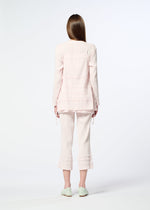 A woman with long brown hair faces away, wearing HaaT’s KYO CHIJIMI TSUCHIKABE apron-style top and matching ruffled cropped pants with a crepe texture in light pink, plus mint green shoes, all set against a plain white background.