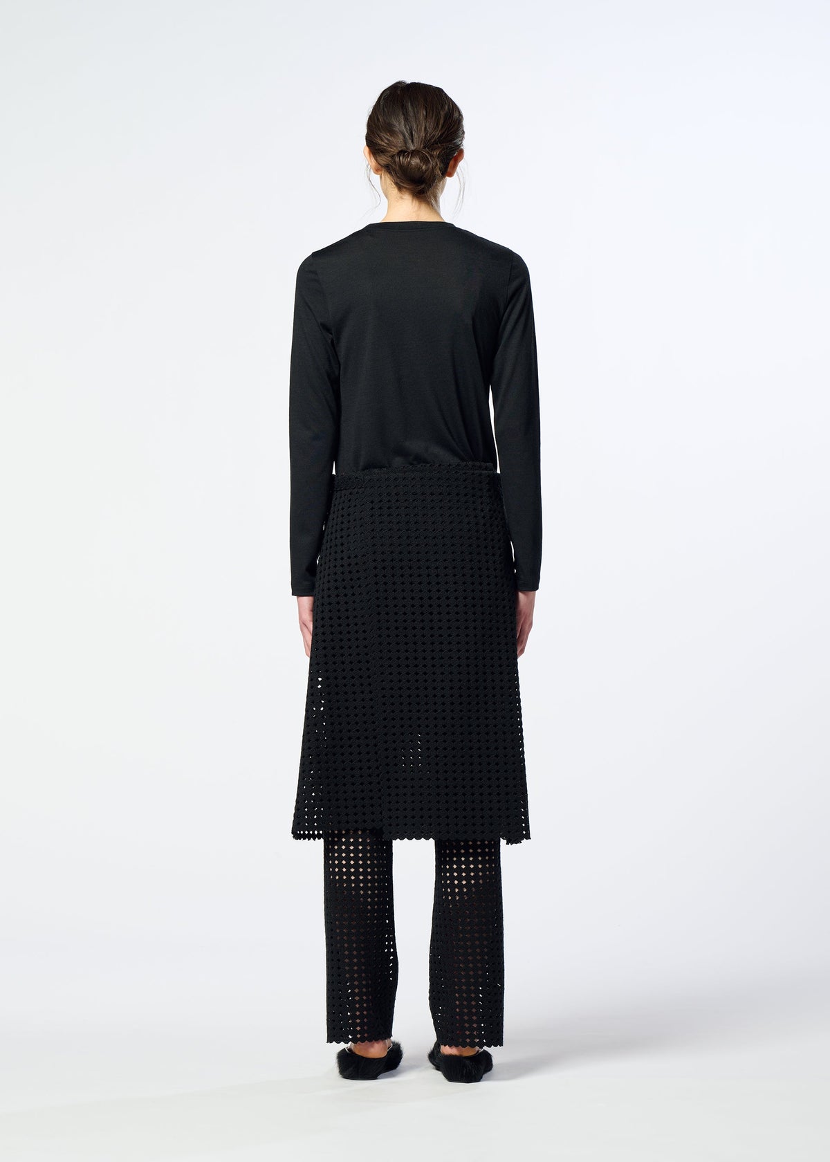A person faces away, wearing a black long-sleeve top, a black textured skirt over HaaT LACY UNDER ponte jersey stretch pants, and black shoes, against a plain light background. view 6 of 6