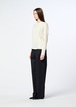 A woman with straight brown hair is seen in profile against a plain white background, wearing HaaT’s W/P WASHER—a round-neck, long-sleeved top crafted from polyester wool jersey with a subtle wrinkled finish—paired with loose black trousers.