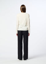 A person stands facing away from the camera, wearing the HaaT W/P WASHER round-neck long-sleeved top in cream and loose black trousers against a plain white background.