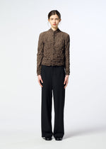 A person stands facing forward, wearing the HaaT KUMO SHIBORI textured brown long-sleeve top with black wide-leg pants and black shoes against a plain white background.