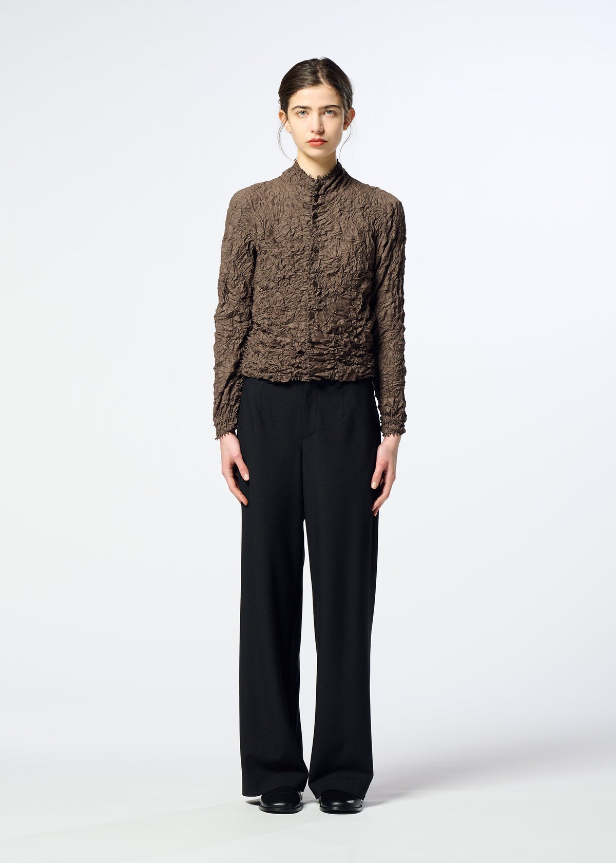 Zoomed view A person stands facing forward, wearing the HaaT KUMO SHIBORI textured brown long-sleeve top with black wide-leg pants and black shoes against a plain white background.