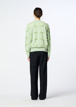 A person faces away, wearing the HaaT RIBBON KNIT in light green with tied ribbons and loose black trousers, set against a plain light background.
