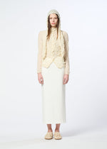A person stands against a white background wearing the HaaT KUMO SHIBORI KNIT SHEER—a cream ramie-blend textured top—paired with a matching bonnet, long white skirt, and cream slippers. Their hair is straight and loose, expression neutral.