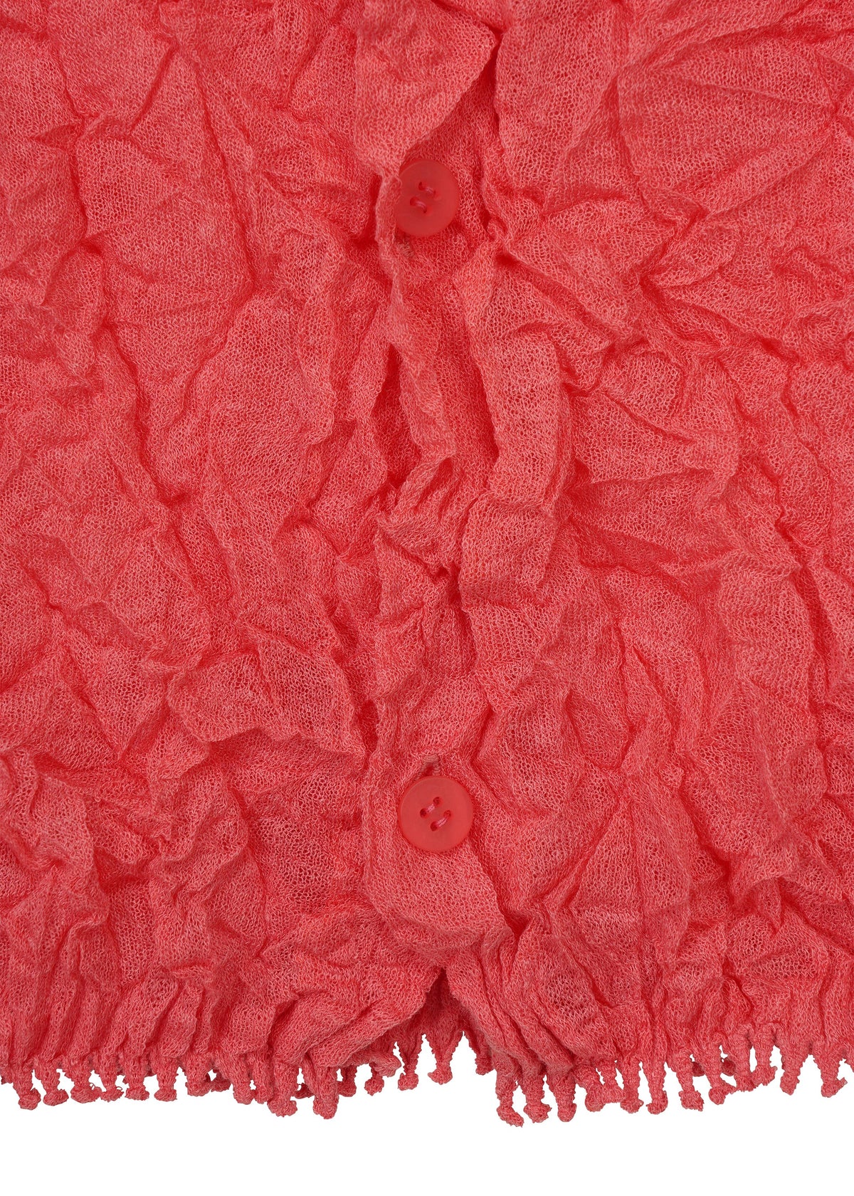 Close-up of a textured, crinkled pink KUMO SHIBORI KNIT SHEER by HaaT, featuring two matching pink buttons and a fringe detail at the bottom edge. view 5 of 9
