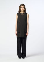 A woman stands facing forward, dressed in HaaT’s AIRY POCKET LAYERS—a sleeveless black tunic featuring two front pockets—paired with loose black pants for a chic layered look. The background is plain and white.