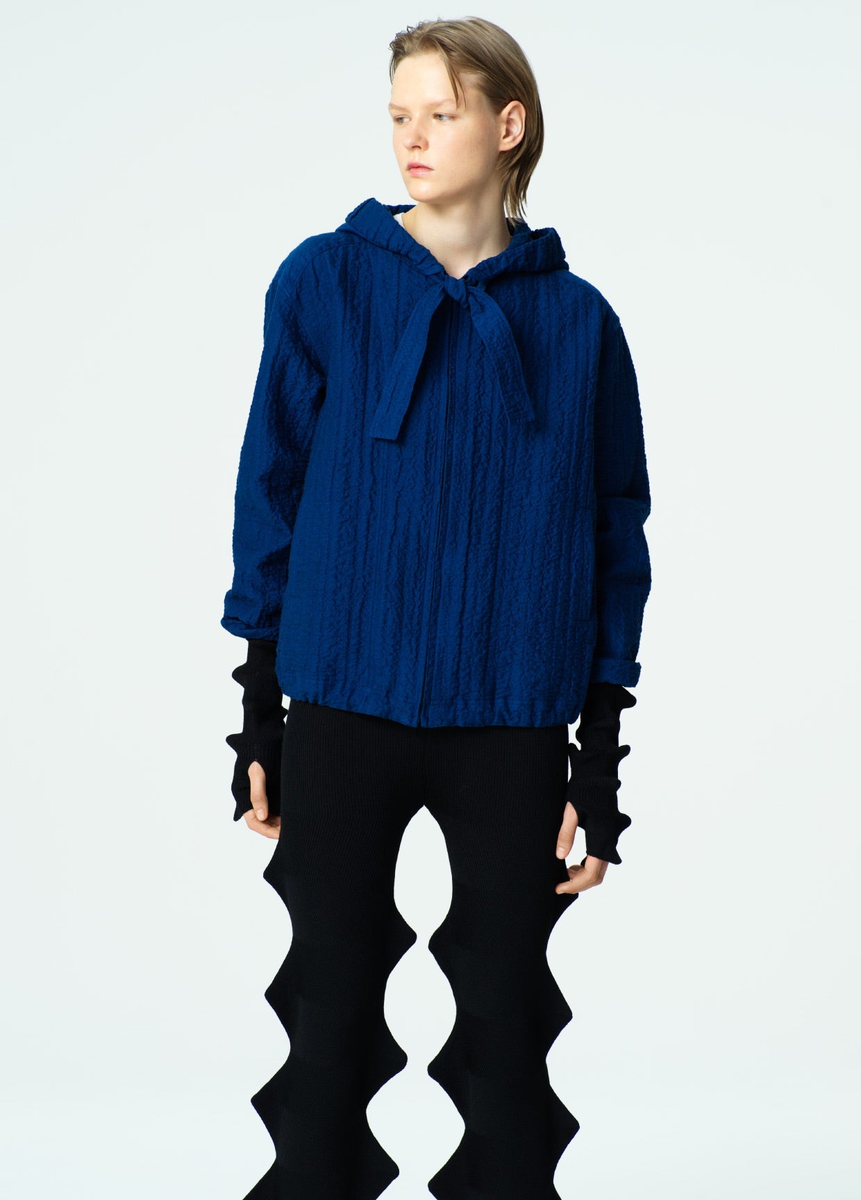 Person wearing a blue sweater with a high collar on a white background