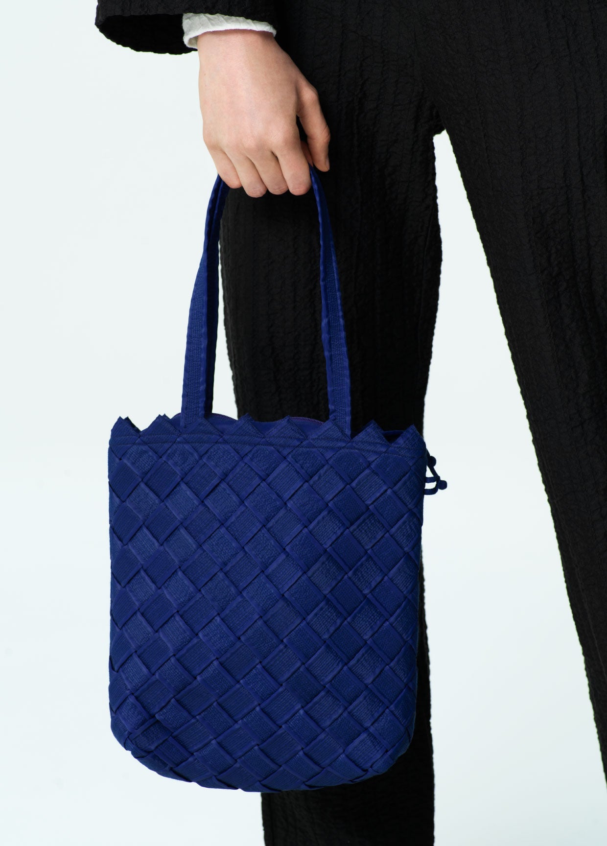 Blue quilted tote bag held by a person against a white background