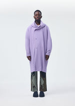 A person stands facing forward, wearing the HOMME PLISSÉ ISSEY MIYAKE MONTHLY COLORS : DECEMBER coat—long, oversized, ribbed lavender with a large cowl neck—paired with black-and-white patterned pants against a plain light background.