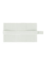 A white, rectangular pleated napkin by HOMME PLISSÉ ISSEY MIYAKE is neatly folded with a matching PLEATS BAND—a tube-shaped fabric ring—encircling its center. - DUOMO GREEN (no.60)