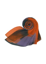 The DAWN STOLE by HOMME PLISSÉ ISSEY MIYAKE is a pleated, tube-shaped scarf with orange, black, and purple sections on white—comfortable for year-round wear.
